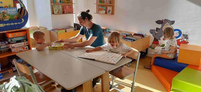 Kinder und Erwachsener lesen und spielen gemeinsam in der Kinderecke