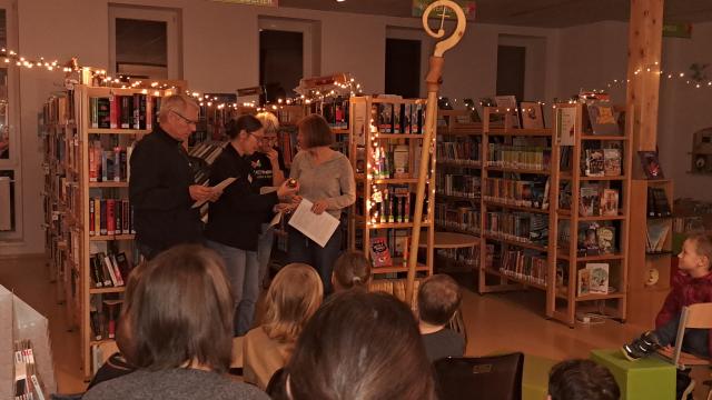 Nikolaus und Mitglieder des Bibliotheksteams "spielen" die Legende von Nikolaus und den drei armen Töchtern: Töchter freuen sich über das Geschenk